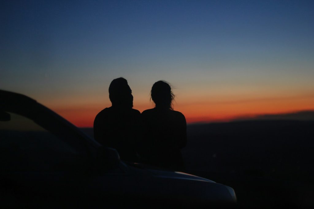 a couple of people sitting on top of a car