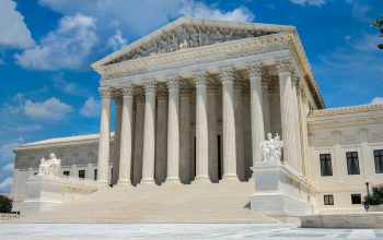 a large white building with columns with United States Supreme Court Building in the background