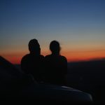 a couple of people sitting on top of a car