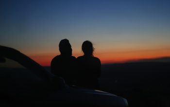 a couple of people sitting on top of a car